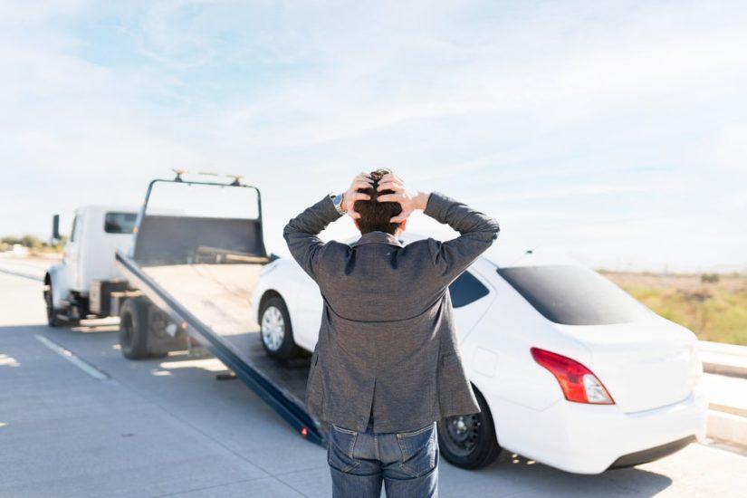 Man Holding His Head Watching His Car Being Towed