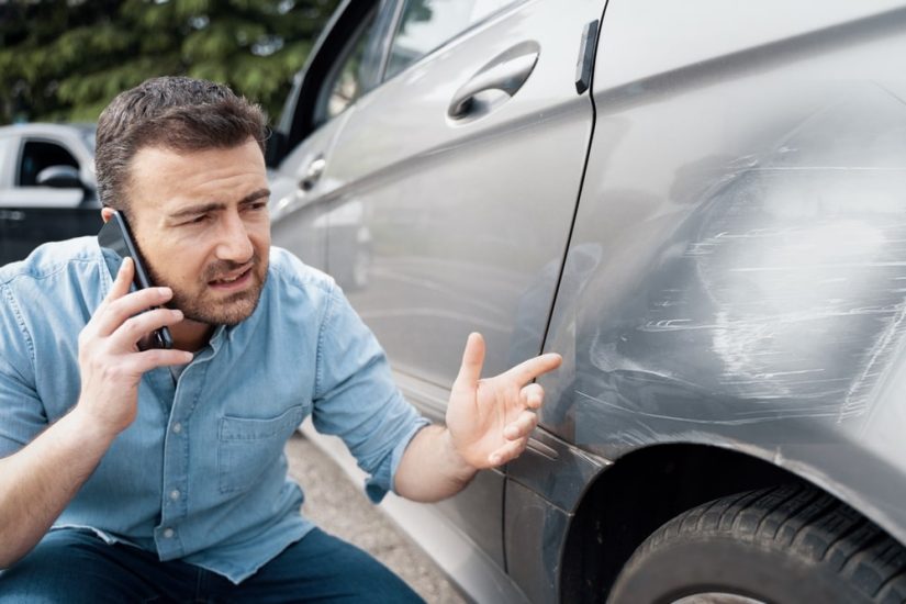Man On The Phone Looking At Scratches On is Car